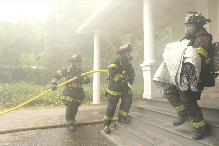 Les pompiers entrent dans la maison tandis que Travis Montgomery (Jay Hayden) en sort avec quelqu'un